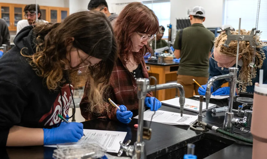 Students in a lab classroom interacting with scientific equipment.
